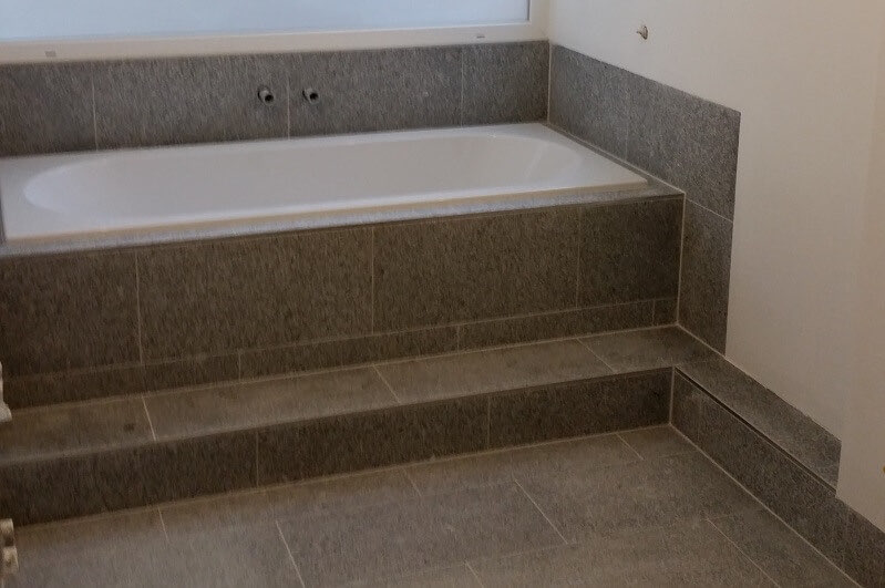 Wannenpodest mit Naturstein-Verkleidung und Stufe