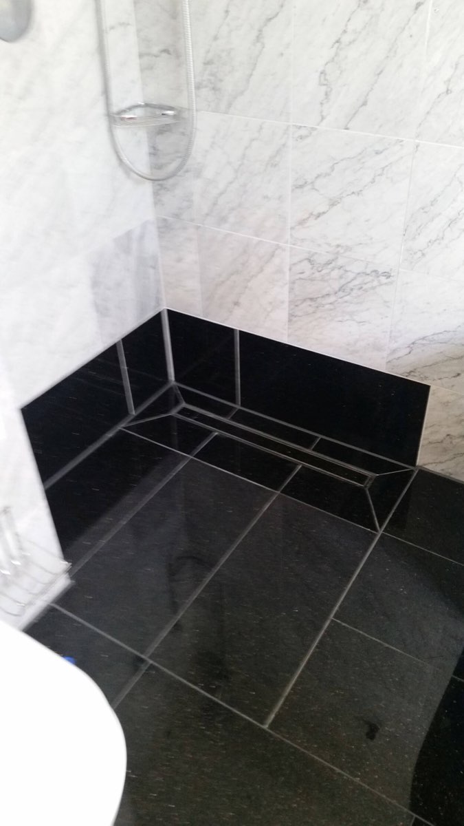 Duschbereich mit schwarzem Marmor und hellem Marmor an der Wand